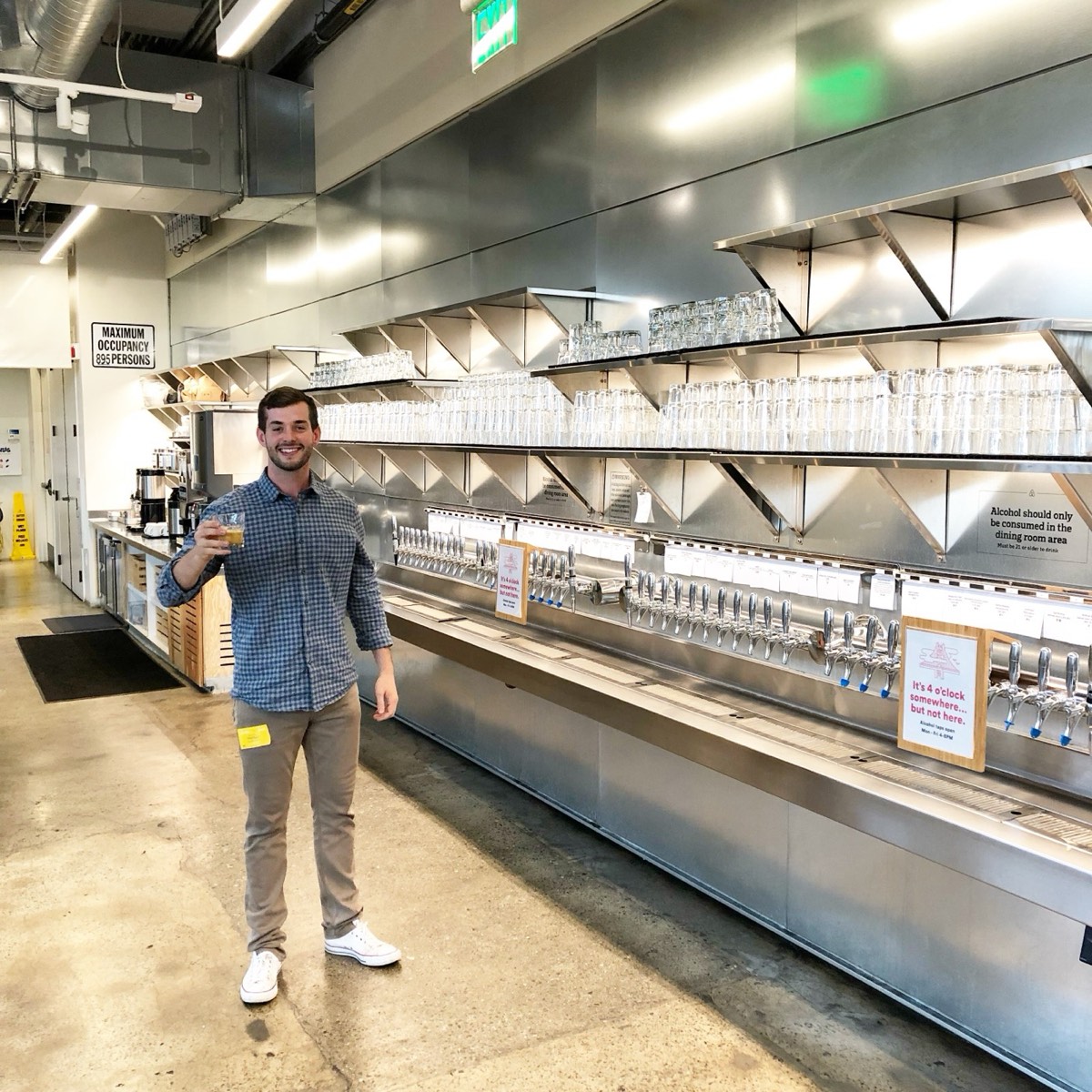 Tom Loebenstein next to a wall of Joyride kombucha and cold brew taps at Airbnb headquarters.